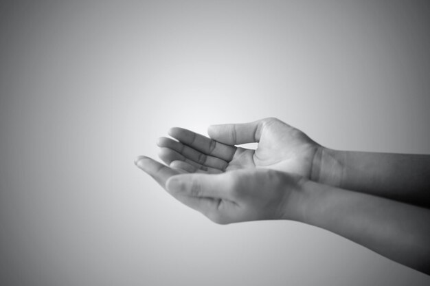 mão de um homem orando e pedindo em branco e preto