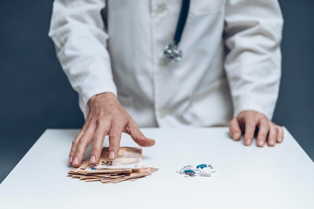 Mão de um médico tomando muita conta ao lado de um monte de pílulas