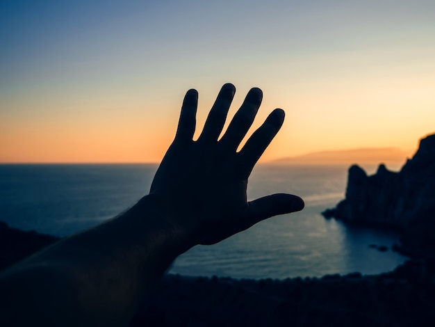 mão de um turista ao pôr do sol no fundo do mar e montanhas na natureza
