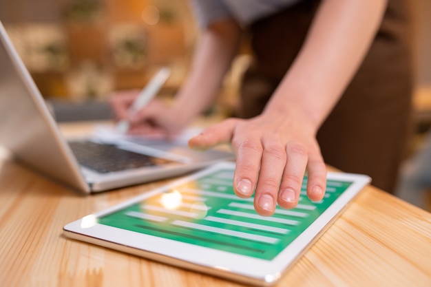 Foto mão de uma jovem empresária contemporânea sobre tablet digital com formulário eletrônico em seu visor durante o trabalho