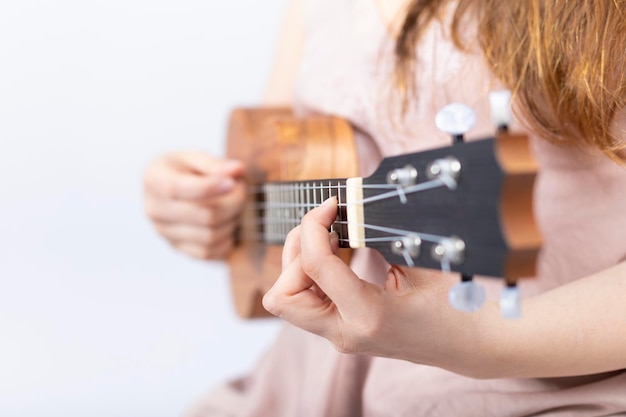 Mão de uma menina tocando cavaquinho, pequeno instrumento de cordas