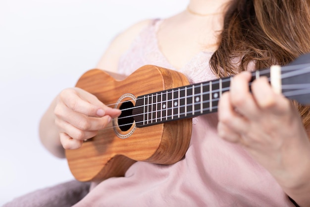 Mão de uma menina tocando cavaquinho, pequeno instrumento de cordas