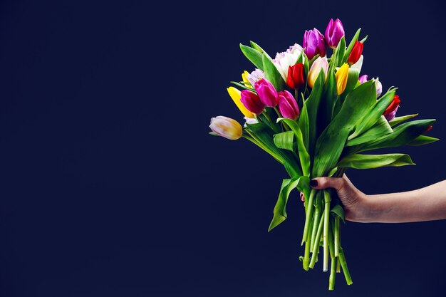 Mão de uma mulher dá um buquê de tulipas