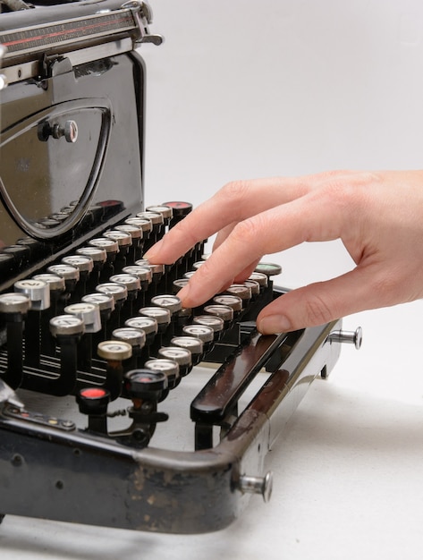 Mão de uma mulher digitando com uma velha máquina de escrever vintage