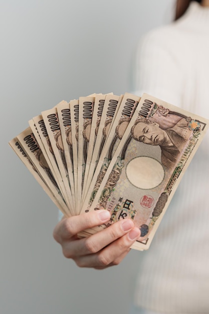 Mão de uma mulher segurando a pilha de notas de ienes japoneses Dinheiro de mil ienes Japão dinheiro Recessão de impostos Economia Inflação Financiamento de investimentos e conceitos de pagamento de compras