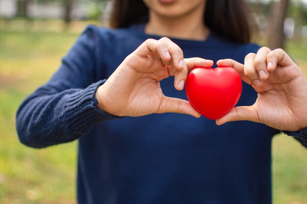 Foto mão de uma mulher segurando coração vermelho