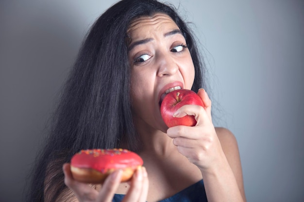 Mão de uma mulher segurando Donut e maçã