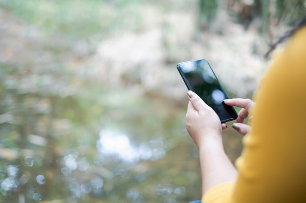 Mão de uma mulher segurando e usando o smartphone, tela preta