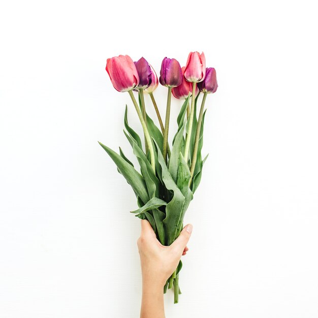 Mão de uma mulher segurando o buquê de tulipas em branco. Camada plana, vista superior