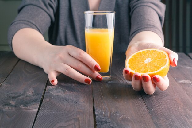 Mão de uma mulher segurando o copo de suco de laranja