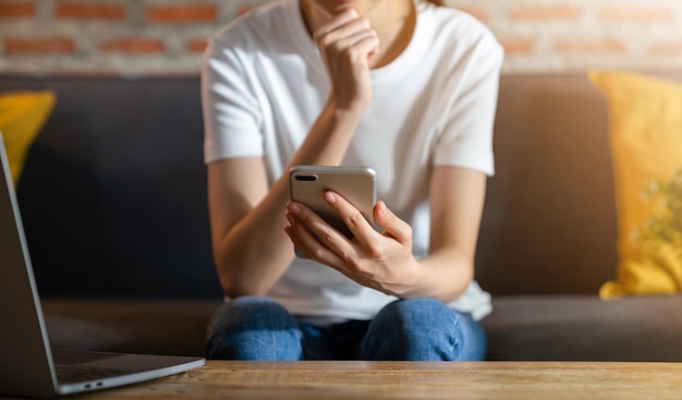 Mão de uma mulher segurando o smartphone com o laptop na mesa, para seu anúncio.