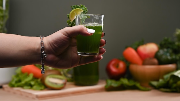 Foto mão de uma mulher segurando um copo de suco vegetal de desintoxicação verde fresco conceito de bebidas saudáveis