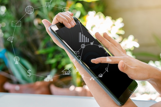 Mão de uma mulher segurando um tablet com mídia social turva e ícones de tecnologia.