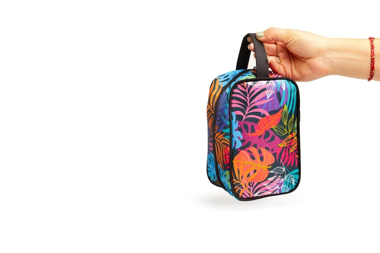 Foto mão de uma mulher segurando uma bolsa de mão colorida em um fundo branco com espaço de cópia