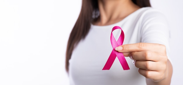 Mão de uma mulher segurando uma fita rosa para conscientização do câncer de mama