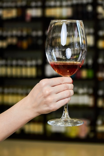Mão de uma mulher segurando uma taça de vinho tinto