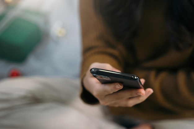 Mão de uma mulher smartphone no fundo do natal