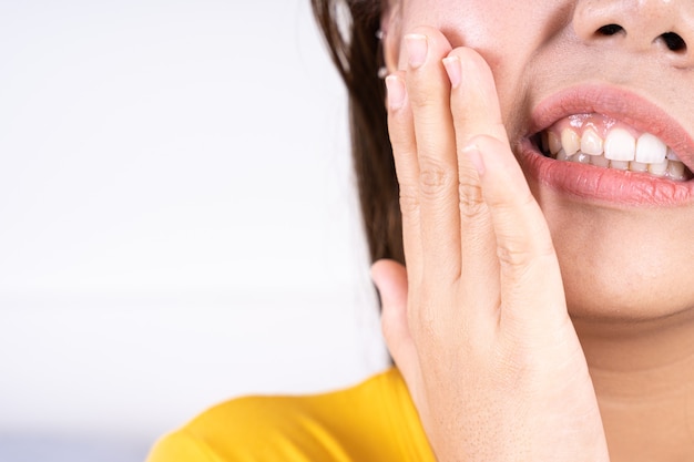 Mão de uma mulher tocando sua bochecha que sofre de dor de dente.