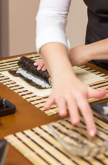 Mão de uma mulher umedecendo com água uma borda de sushi