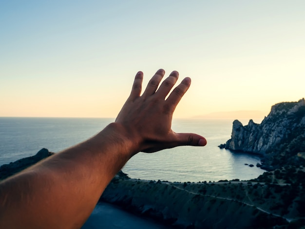 Foto mão de viajante turístico homem no contexto do mar e céu