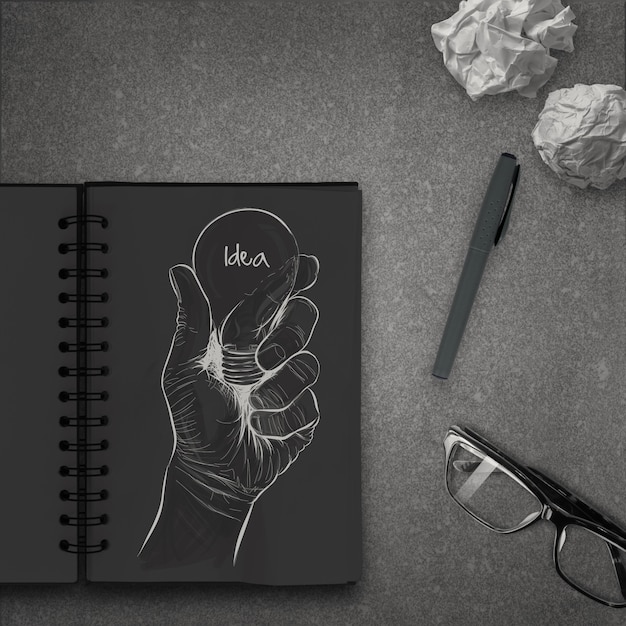 Mão desenhada lâmpada com palavra idéia no caderno escuro como conceito