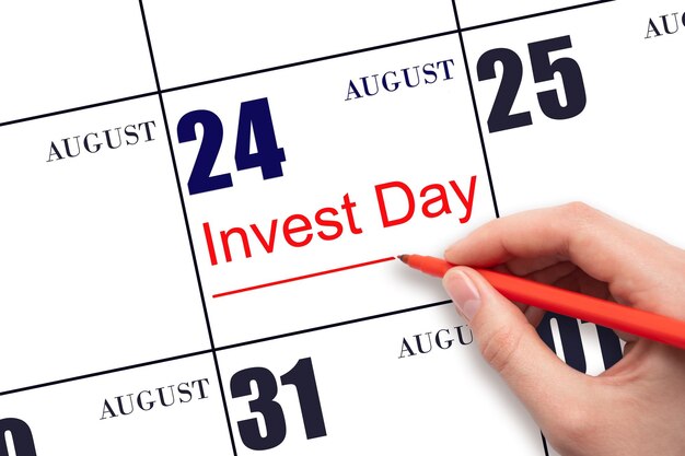 Mão desenhando linha vermelha e escrevendo o texto invest day na data do calendário 24 de agosto conceito de negócios e financeiro