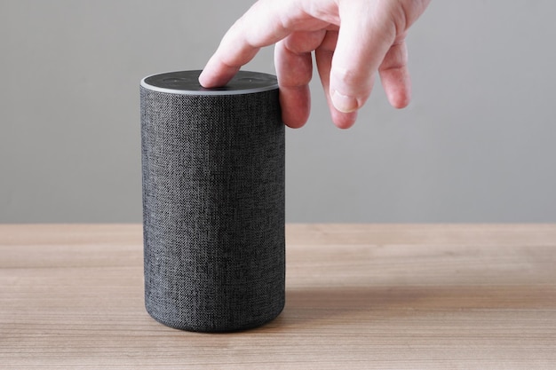 Mão desligando o microfone de alto-falante inteligente