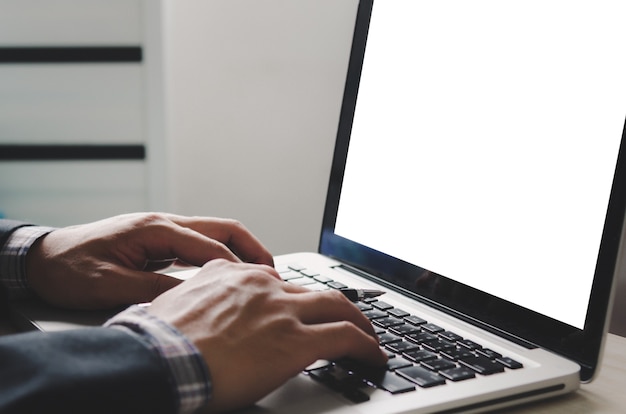 Mão digitando no teclado do laptop e simulando a tela do computador em branco. espaço em branco na tela para mídia de publicidade