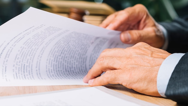 Foto mão do advogado masculino segurando o documento na mesa no tribunal