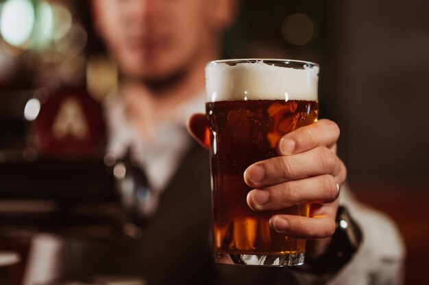 Mão do barman com um copo de chope light com espuma em bar