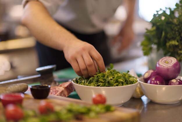 mão do chef servindo salada de legumes no prato na cozinha do restaurante