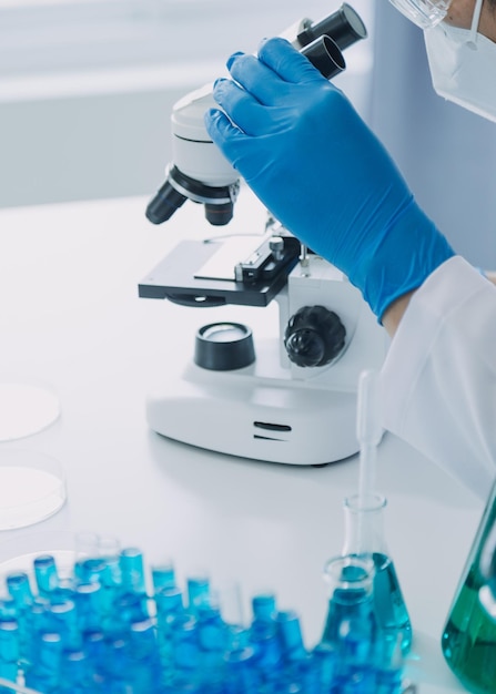 Mão do cientista com tubo de ensaio e frasco no fundo da bandeira azul do laboratório de química médica