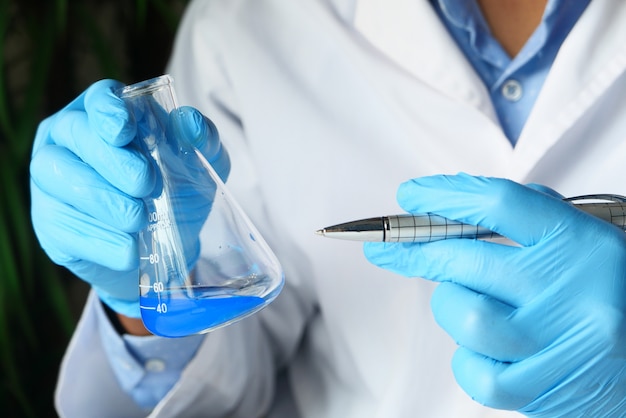 Mão do cientista segurando o vidro de laboratório de cima para baixo.