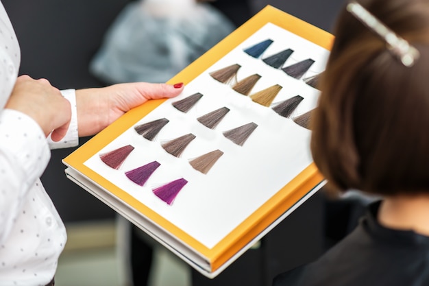 Mão do estilista segurando a paleta de amostras de tintura de cabelo.