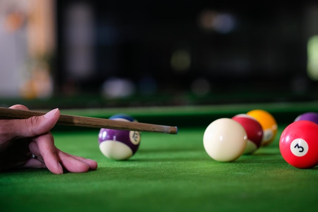 Mão do homem e braço Cue jogando sinuca ou preparando-se para atirar bolas de sinuca em uma mesa de bilhar verde Bolas de sinuca coloridas no friso verde