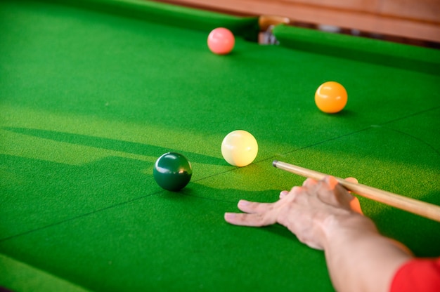 Mão do homem jogando sinuca no bar com bola de snooker