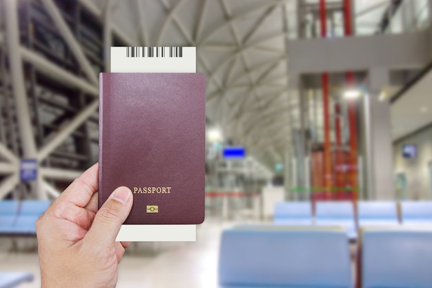 Mão do homem segurando passaporte internacional enquanto espera na frente do balcão para check-in