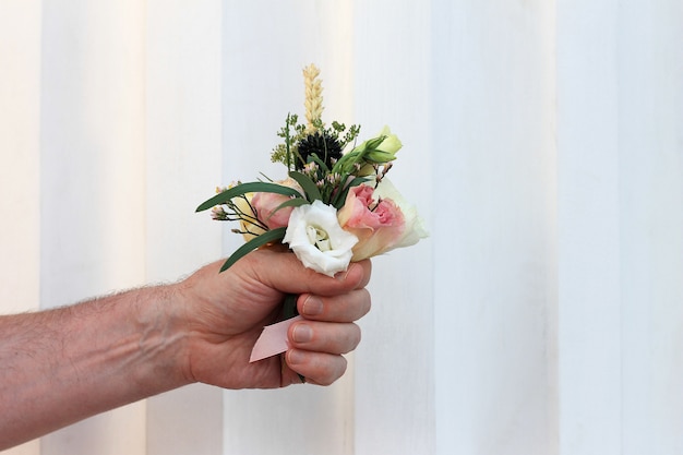 Mão do homem segurando um pequeno buquê lindo de flores