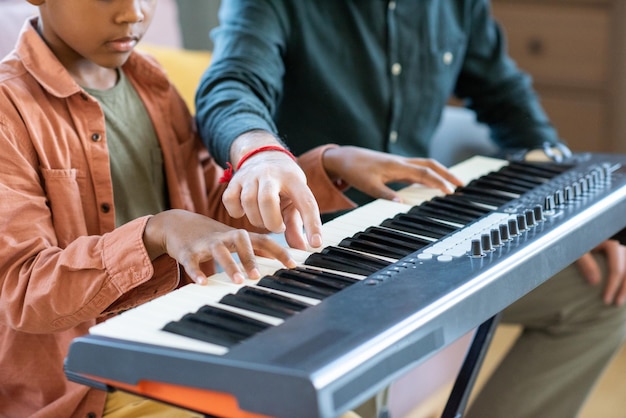 Mão do jovem professor de música apontando para uma das teclas do teclado de piano