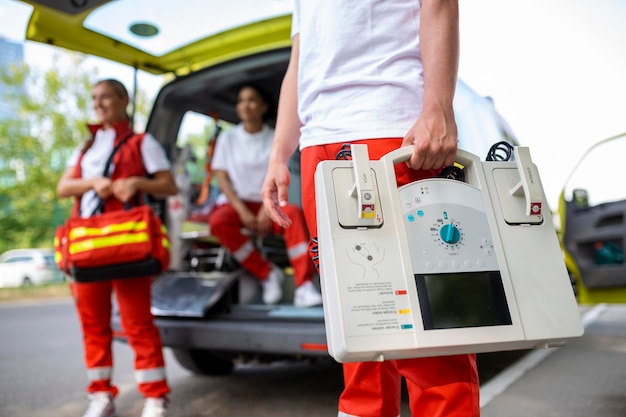 Mão do médico com desfibrilador equipes do serviço médico de emergência estão respondendo a um acidente de trânsito