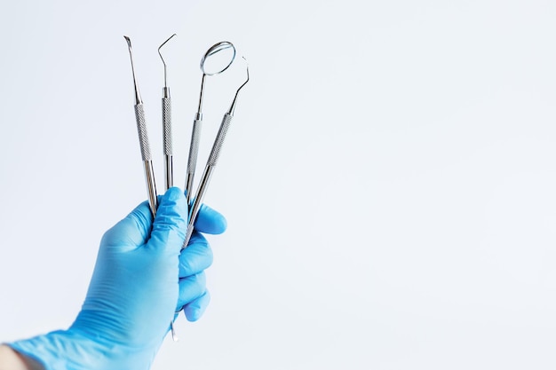 Foto mão do médico segurando ferramentas de odontologia para atendimento odontológico de dentes e tratamento sobre fundo branco