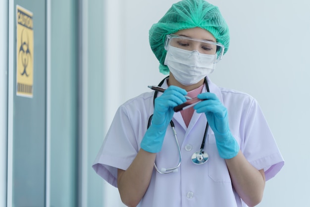 Mão do médico segurando um tubo de ensaio com amostra de sangue contaminado dentro