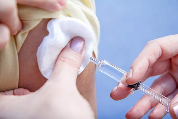 Mão do médico segurando uma seringa para vacinação no braço do paciente para prevenção do enjoo da gripe