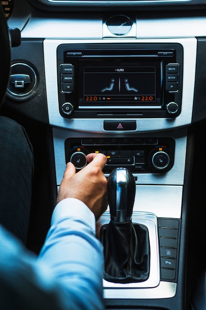 Mão do motorista, ajustando o botão de áudio no carro