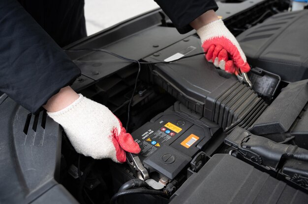 Mão do motorista verificando a condição da bateria do carro.