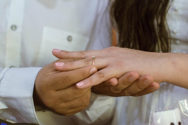 Mão do noivo colocando o anel na mão da noiva para propor à sua noiva