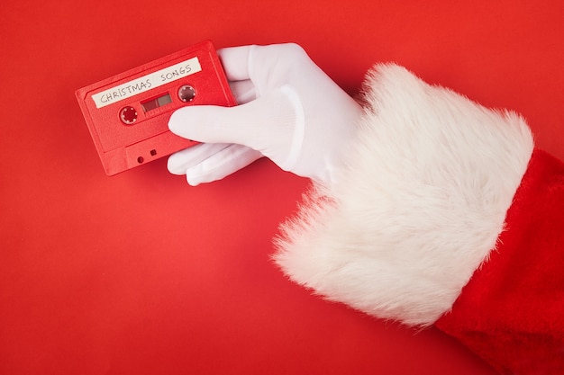 Mão do papai noel segurando uma fita cassete com canções de natal gravadas