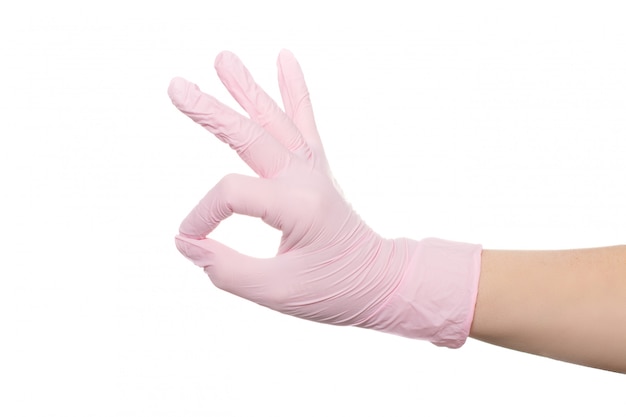 Mão em uma luva médica rosa sobre fundo branco.