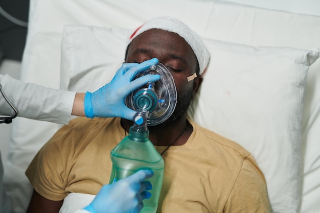 Mão enluvada de enfermeira ou cuidador segurando balão e máscara de oxigênio