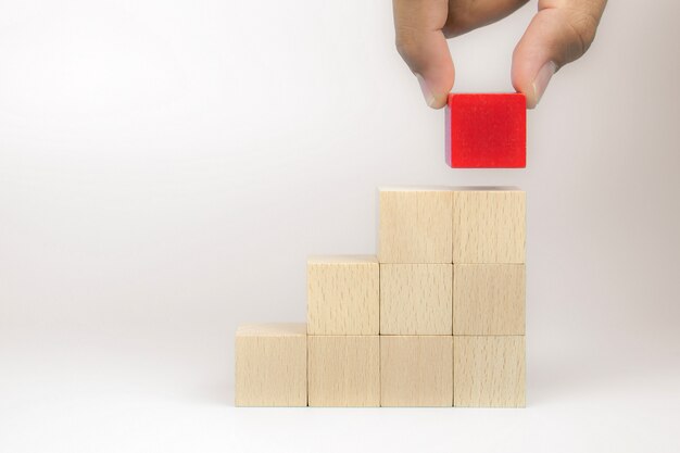 Mão, escolhendo um brinquedo de bloco de madeira de forma de cubo empilhados em forma de triângulo sem gráficos.